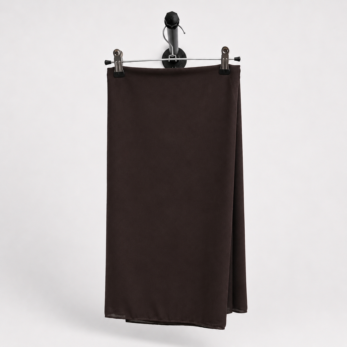 A dark brown, solid-colored fabric panel or curtain hanging from a black metal hanger with two silver clips against a light gray background.